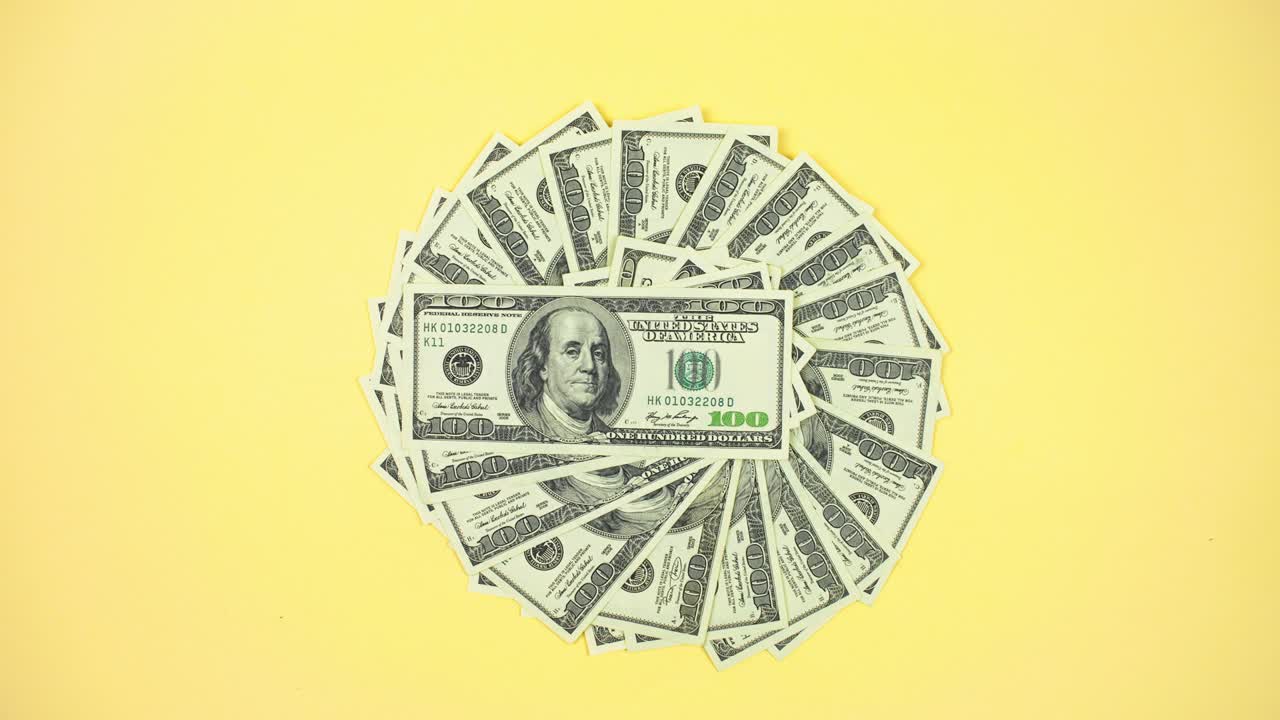 Banconote americane da cento dollari in 4K ruotano in cerchio e il loro numero sta aumentando. Sfondo giallo