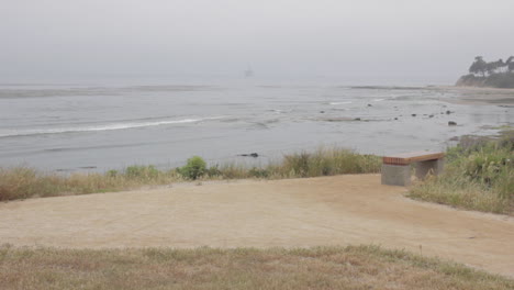 foggy day at the pacific ocean, cliffs overlooking beach, slider shot movement