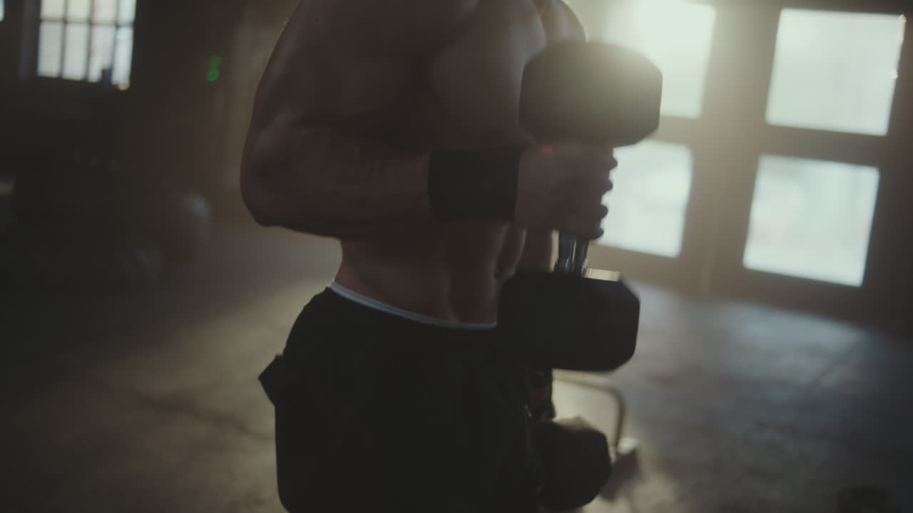 Muscular Man Working Out with Dumbbells in a Gym
