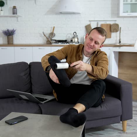 man on sofa at home. young man resting at home, brushing his socks