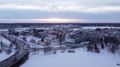 sunset cloudy sky over snowy tornio city in wintertime aerial pullback