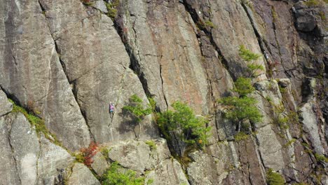 aerial footage push in on young female climber on cliff in maine