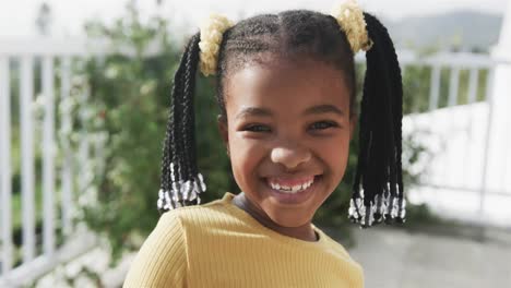 portrait of happy african american girl smiling on sunny terrace, slow motion
