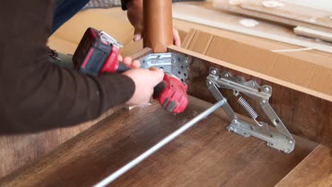 man assembling furniture with a drill