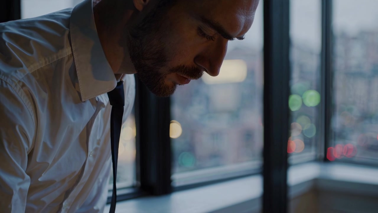 Pensive Businessman in White Shirt Looking Down by Window