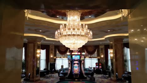 a luxurious gambling haven with elegant chandelier overlooking slot machines and gaming tables in a high-end casino atmosphere filled with glamour and excitement