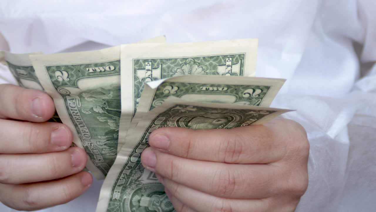 의사나 간호사가 달러 지폐를 세고 있습니다.