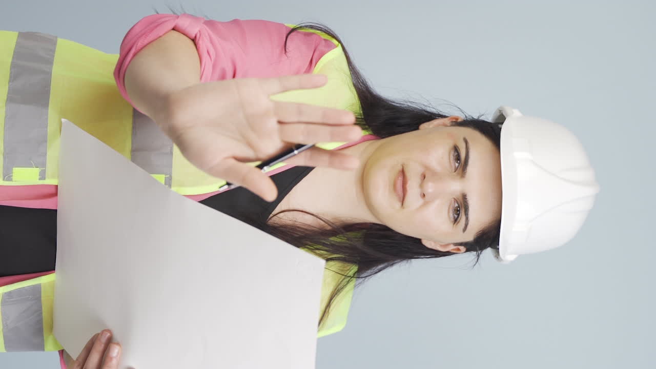 vídeo vertical del ingeniero mira a la cámara y hace una señal de alto.