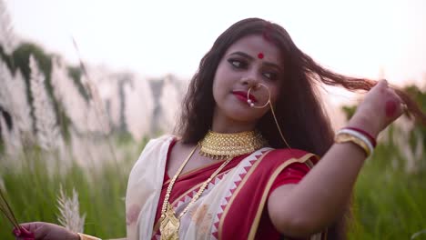 una mujer india recién casada, alegre y juguetona, juega con su hermoso cabello largo y rizado en un campo al aire libre al atardecer o al amanecer