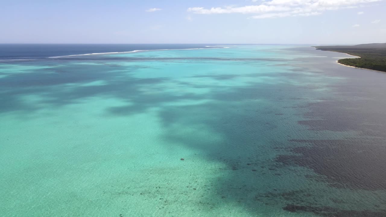 Drone aerial pan down over a blue reef on a cloudy day in New Caledonia