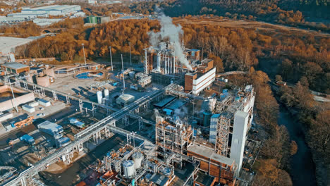 Aerial-footage-moving-towards-a-large-industrial-chemical-plant,-showing-pipelines,-metal-structures,-cooling-towers-and-chemical-storage