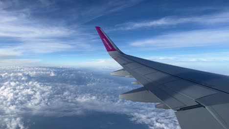 wizz air plane wing in the air in the clouds during the day 4k