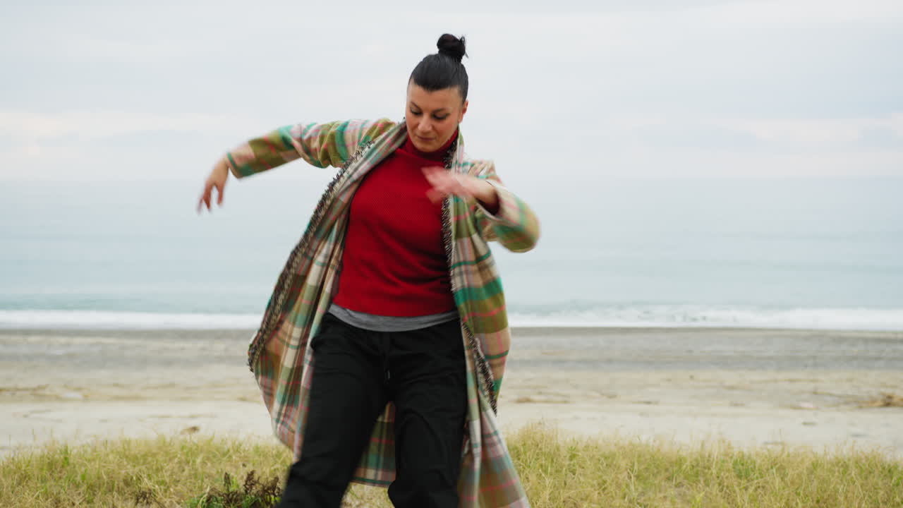 Una donna esegue passi di danza energici sulla spiaggia vicino al mare italiano di sera.