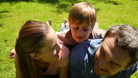 little boy and parents smiling at camera in the park while little boy makes funny faces