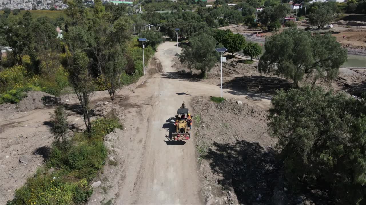 Droneudsigt over gravemaskiner, der passerer gennem et byparksprojekt i Mexico, 4K