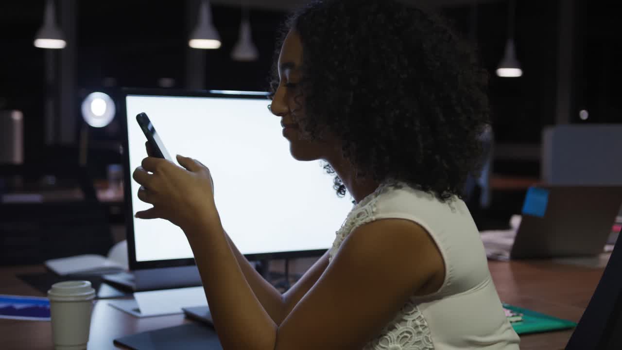 Businesswoman working and using phone in a modern office by night