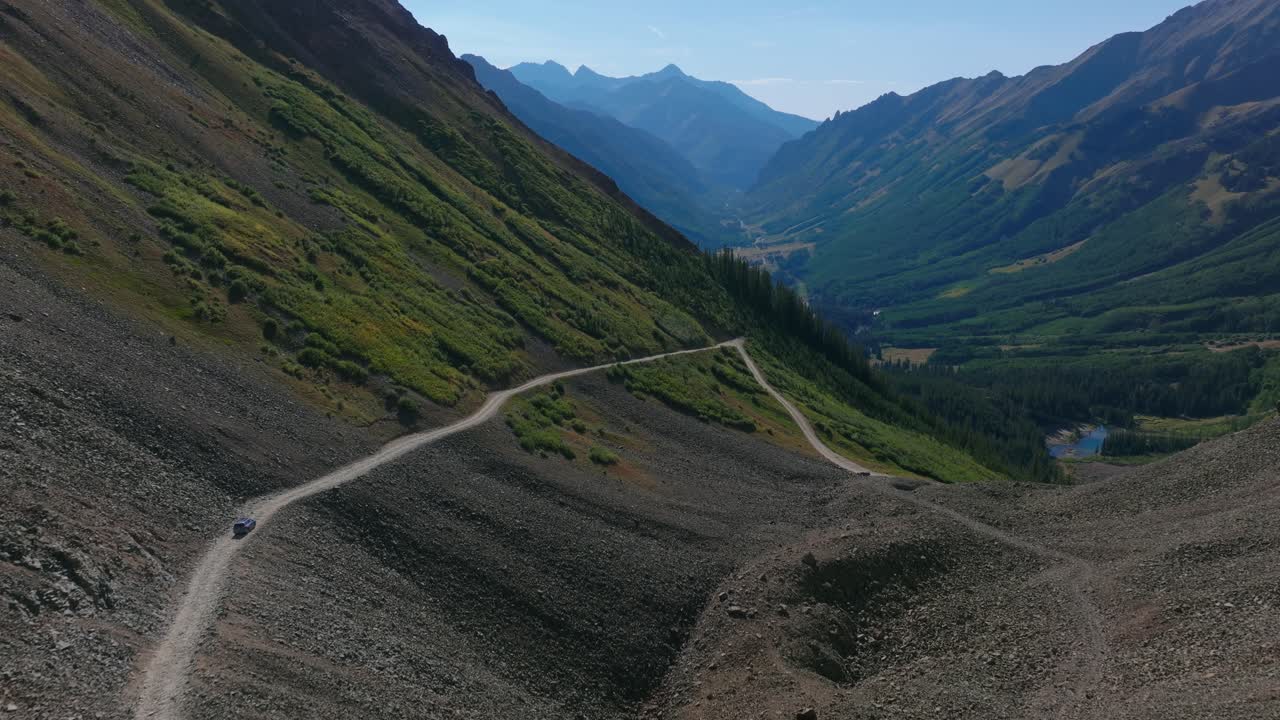 Ophir Pass reveals a steep cliffside road carved into unstable mountain slopes, rugged alpine environment of the San Juan Mountains Colorado, cars navigate