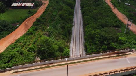 beautiful jib up of a bridge across a long railroad with cars driving over the bridge in rural nigeria, africa