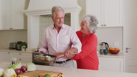 Mujer-Mayor-Caucásica-Abrazando-A-Su-Marido-Por-Detrás-En-La-Cocina-De-Casa