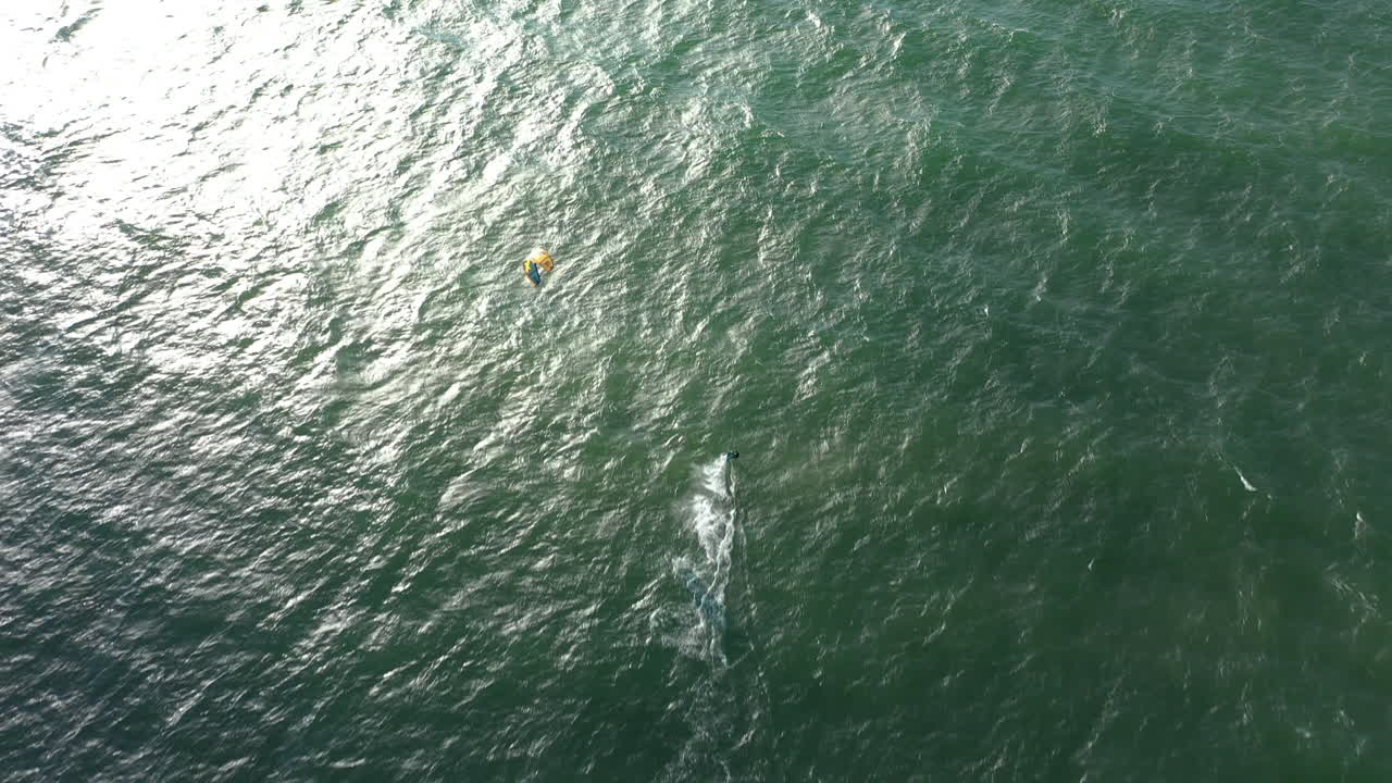 antena: vista superior de un surfista aislado montando olas en un mar báltico de color verde