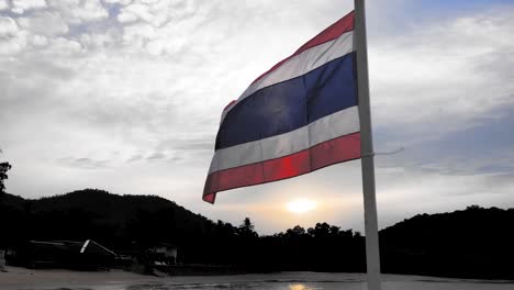 thai flag waving on the wind against the sky at mataphon pier in thailand during sunrise