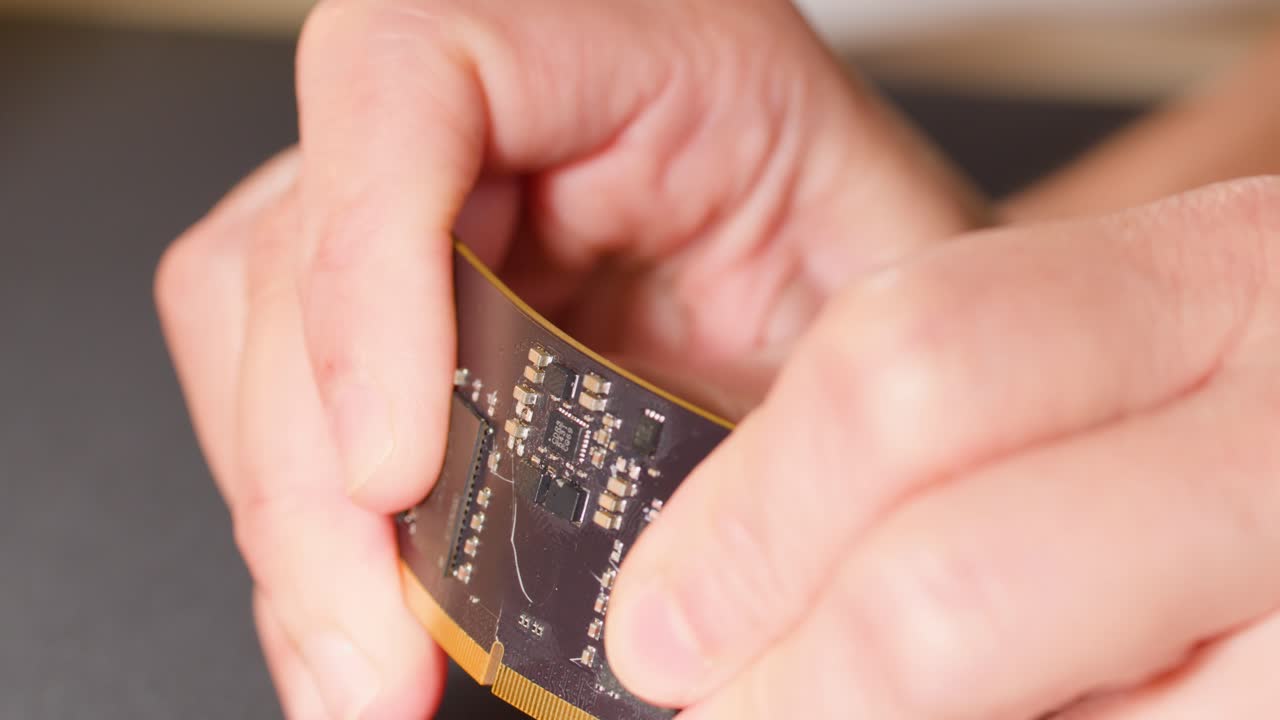Close-up shot of hands demonstrating the flexibility of a modern electronic circuit board with chips