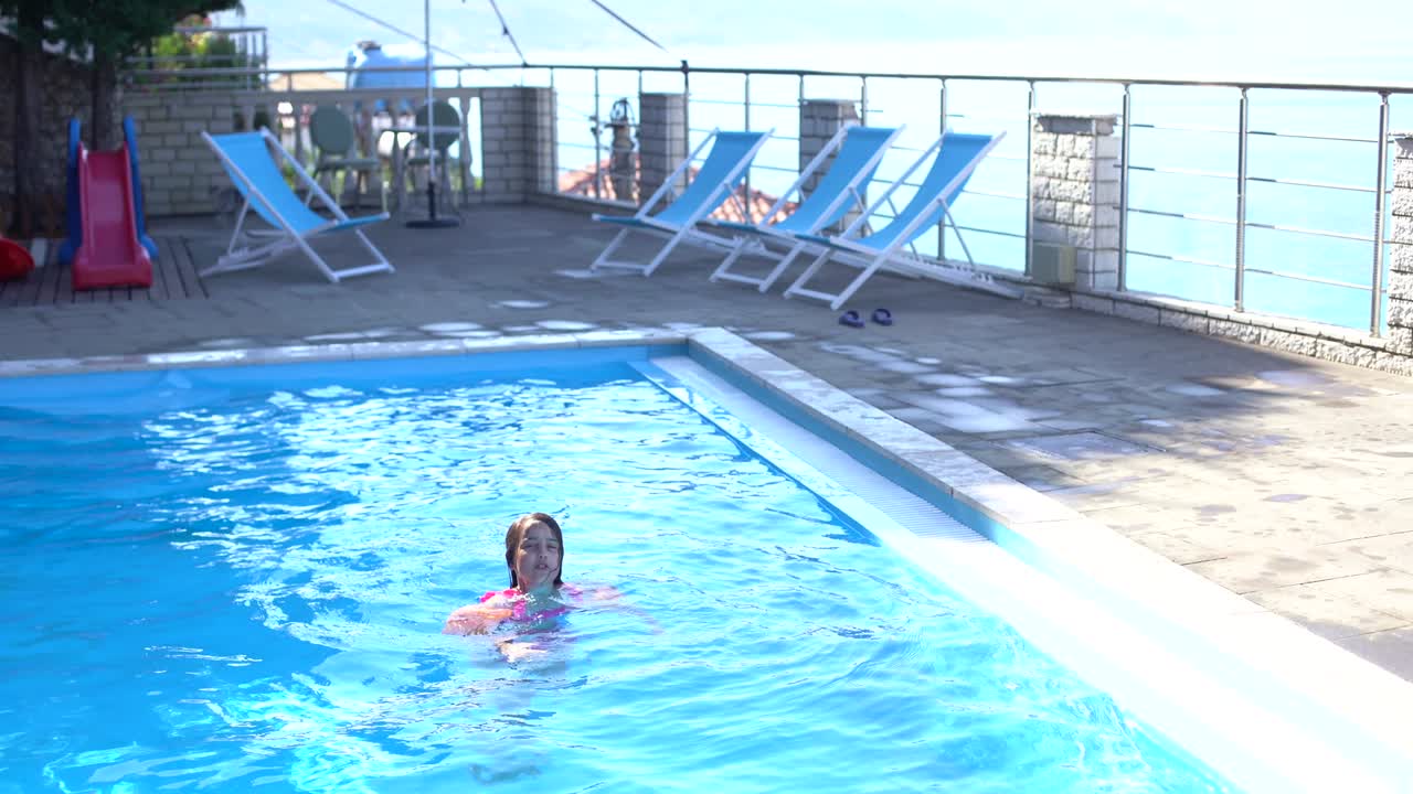 야외 수영장에서 수영하는 예쁜 어린 소녀와 부풀어오르는 팔로 재미를