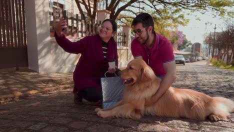 man, woman, and golden retriever dog on a street taking a selfie