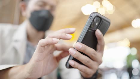 수술 마스크를 착용한 젊은 사업가가 인터넷에 연결된 스마트 폰을 통해 고객들과 비디오 컨퍼런스를 하고 있습니다.