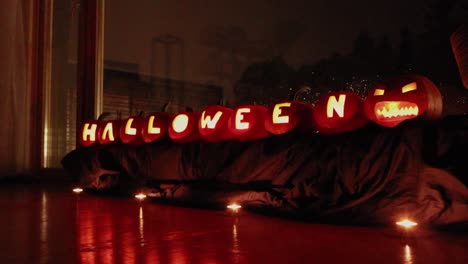 halloween pumpkins placed in front of a window during a rainy night or evening