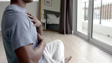 african american man doing yoga and meditating at home, slow motion