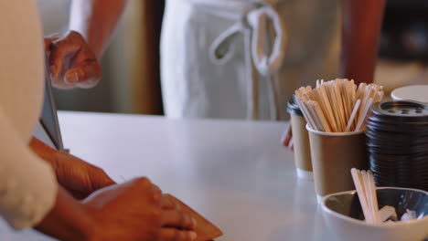 mujer afroamericana que usa tarjeta de crédito haciendo pagos cajera amigable sirviendo clientes gastando dinero en transacciones inalámbricas comprando café apoyando pequeños negocios cafetería cerrar manos