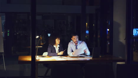 a business man and woman working overtime together