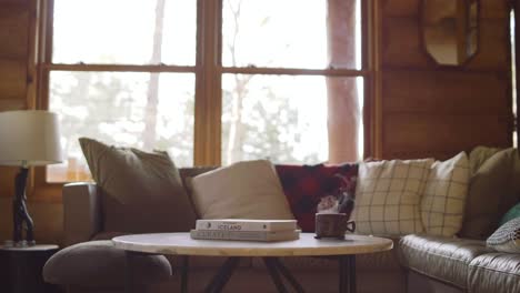 interior acogedor de la cabaña con café humeante y libros en una mesa junto a una ventana