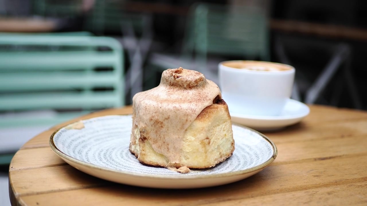Delizioso Rotolo alla Cannella con Caffè su un Tavolo di Legno in un Caffè all'Aperto