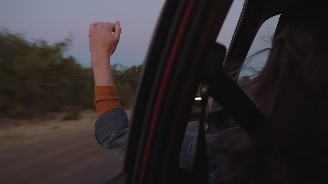 차 안에서 손을 밖으로 내밀고 창문을 들고 손가락을 통해 바람이 불어오는 느낌으로 시골에서 도로 여행을 떠나 여름 휴가를 즐기며 해가 뜨면 도로에서 자유를 즐기고 있습니다.