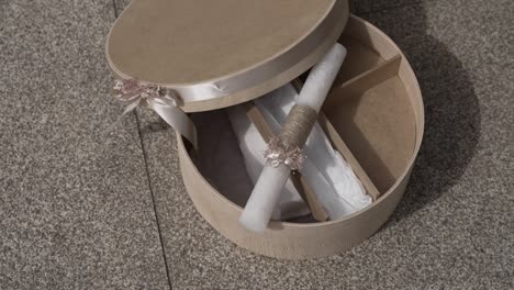 decorative round box with a baptismal candle and ribbon on a stone surface