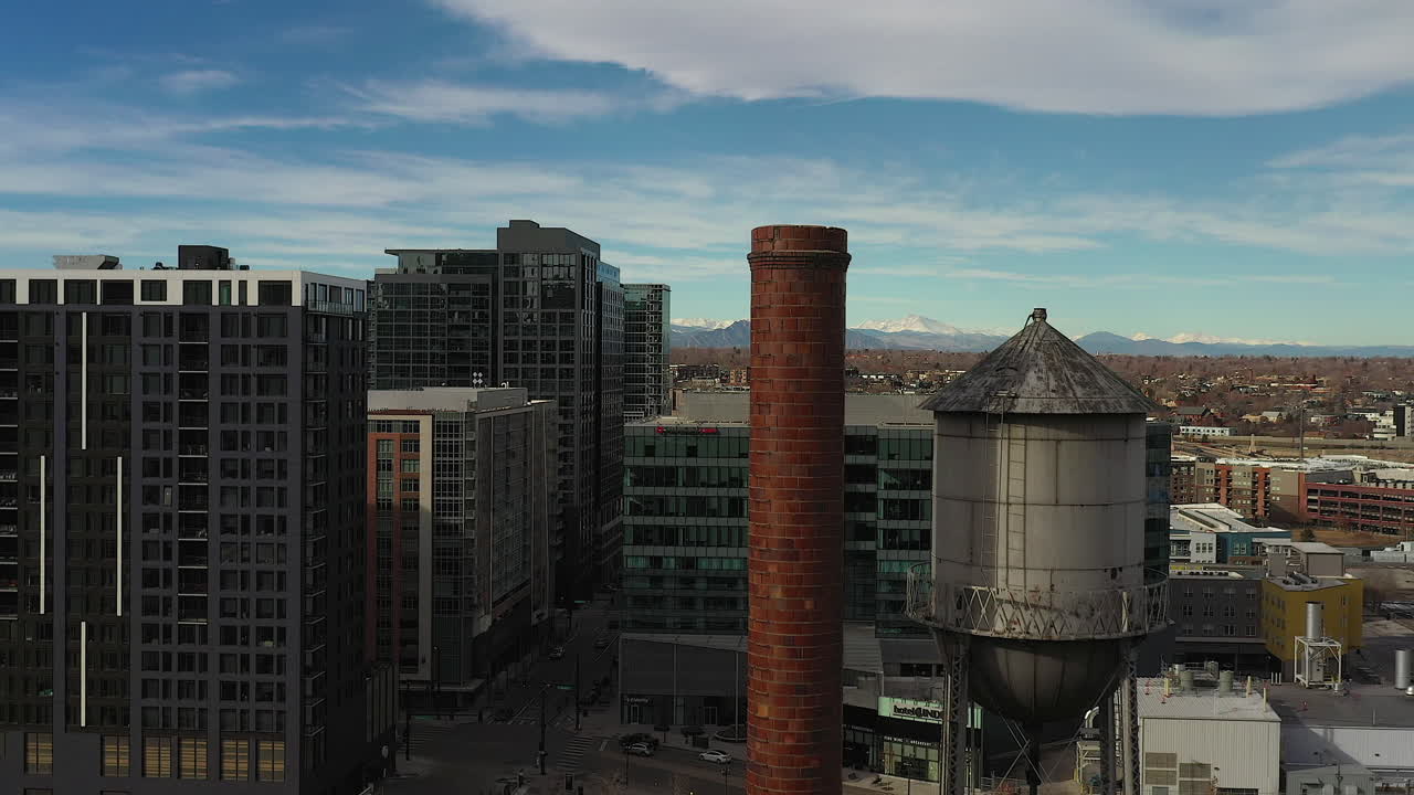 Rising aerial drone footage of the Meadow Gold Butter building and the water tower and chimney stack on top, in Downtown Denver, Colorado