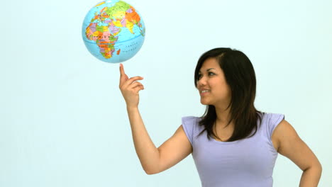 smiling woman spinning globe on finger