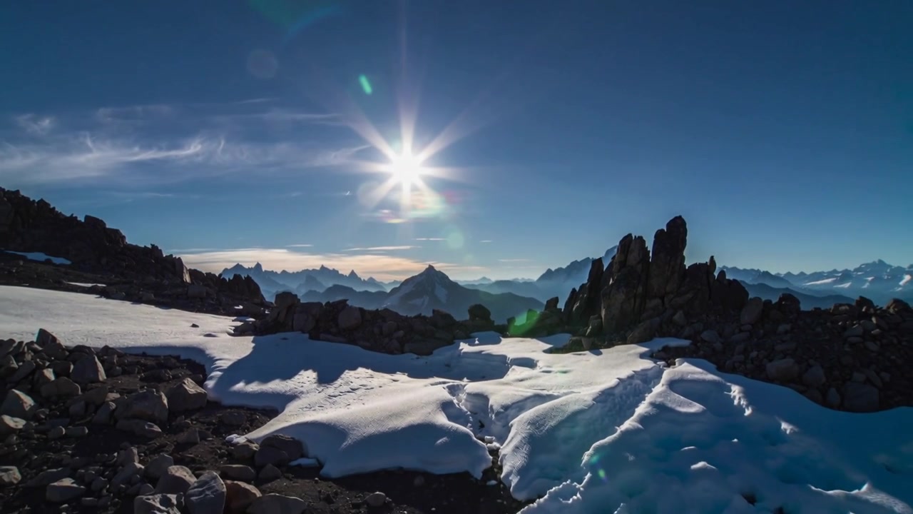 Viser en høj alperyg, der afslører smeltekanaler, mens solen sænker sig og blødgør lyset, med lens flare.