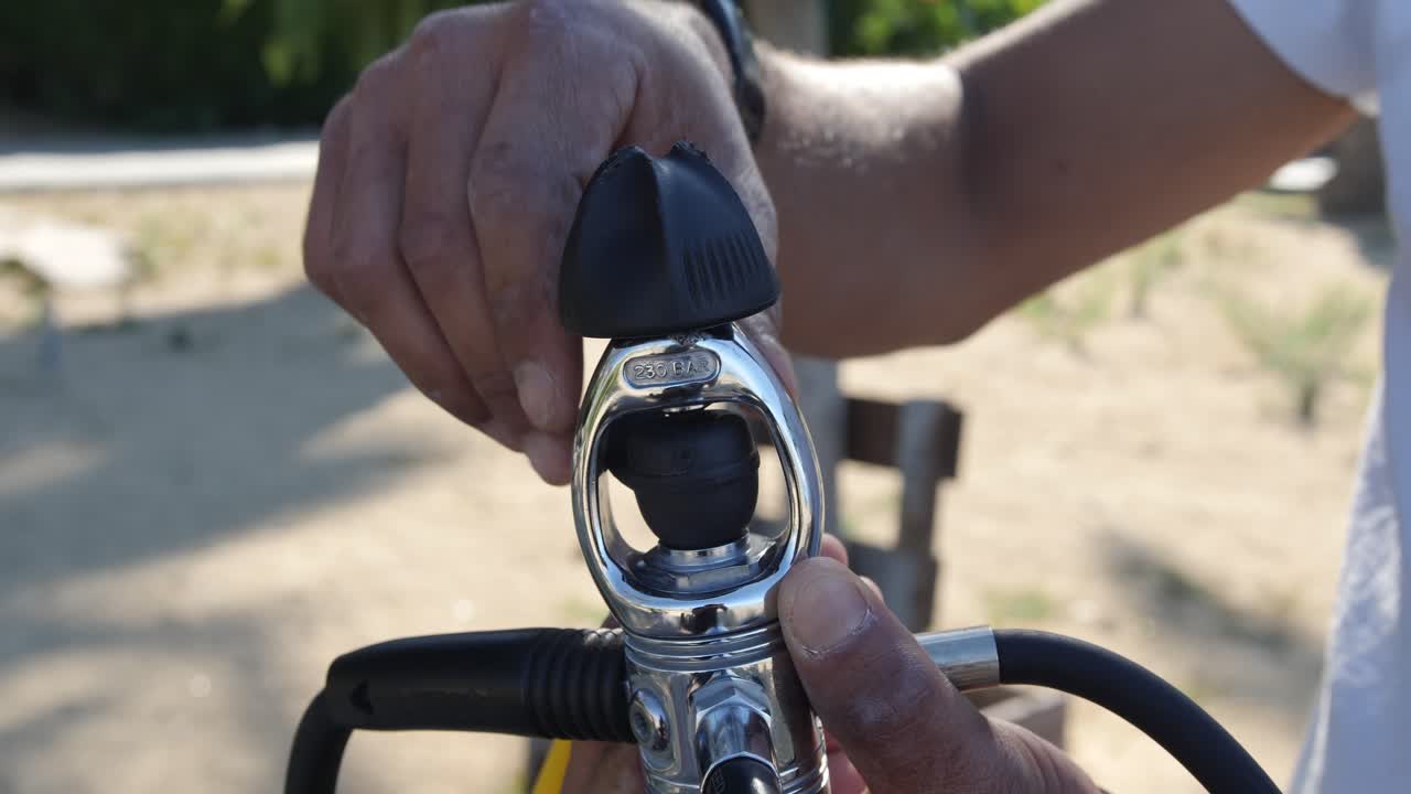 primer plano de cómo aflojar el tornillo del yugo en un regulador de buceo en preparación para conectarlo al tanque de aire