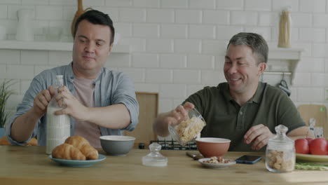two men having breakfast together in a kitchen.