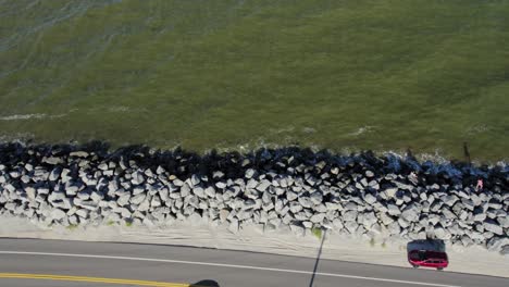 slow motion flight above a rock sea wall, highway and gulf waters