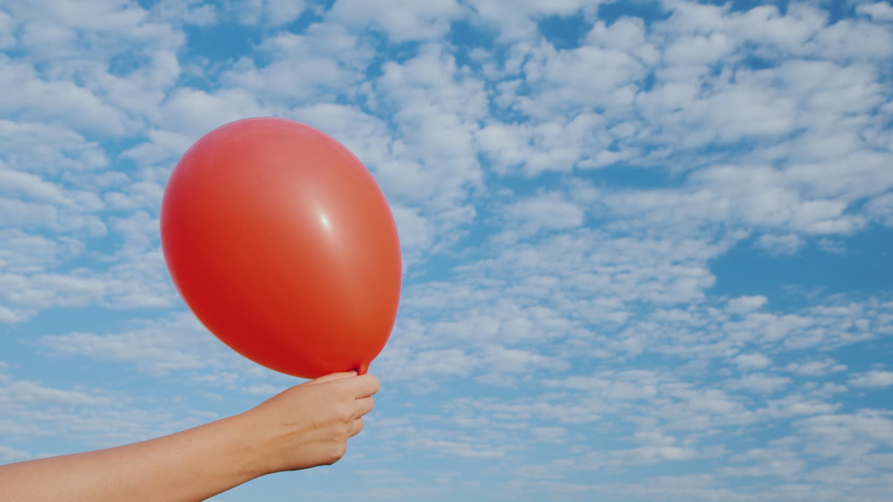 빨간 공기 풍선에서 공기가 나오고 푸른 하늘을 배경으로 절름발이가 됩니다.