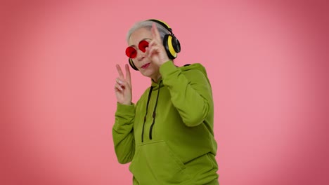 senior woman listening music on headphones dancing disco fooling, having fun, gesticulating hands