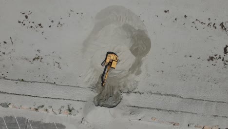 Aerial-drone-birdseye-footage-of-an-excavator-moving-the-sand-at-Sandy-beach-in-Cohasset,-MA-USA