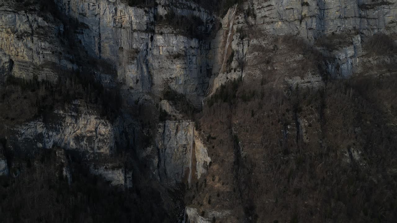 A beautiful waterfall falling on the dark rocks of the Swiss Alps in the early evening