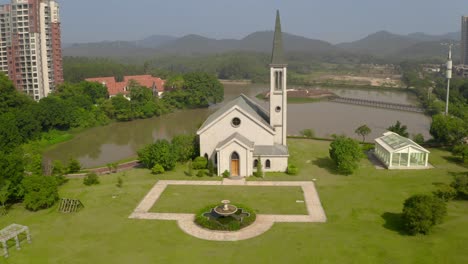 catholic style church building without a cross surrounded with green grass fields on a bright clear day