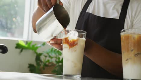 mid section of african american male barista making coffee using coffe machine at cafe