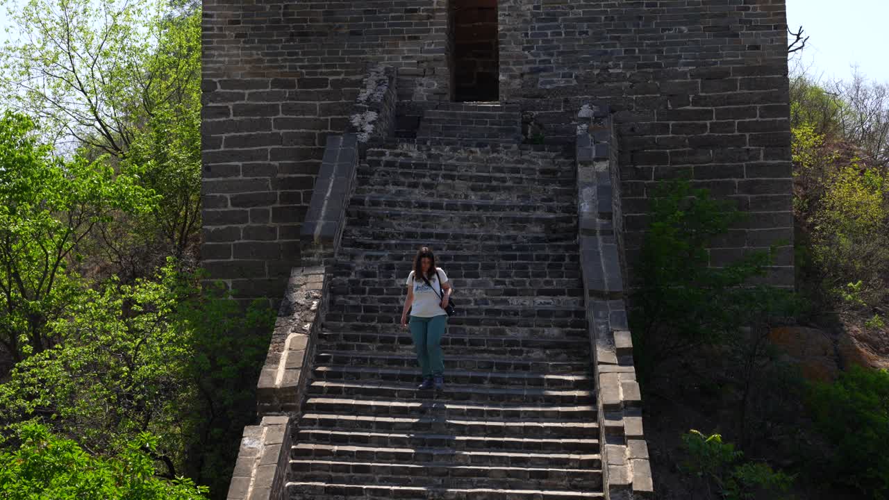 Handheld shot of woman descending stairs from an old watchtower in Jinshanling section of Great Wall